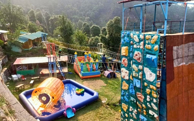 Adventure park area with a climbing wall, inflatable bounce house, and zorbing pool